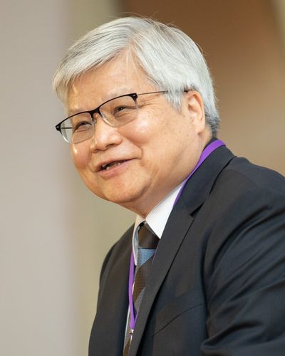 C. C. Wei smiling, grey-haired and in glasses, in a dark suit