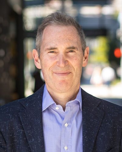 Andy Jassy in a dark jacket and open-collared blue shirt