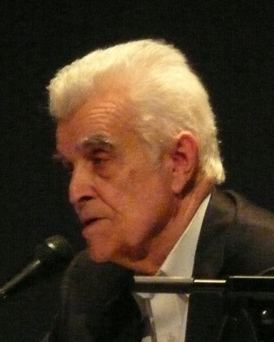 René Girard, an older man with thick white hair, speaking into a microphone
